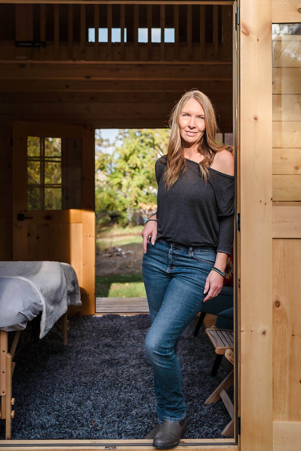 spiritual entrepreneur leaning in doorwary of wooden outdoor studio with beautiful light