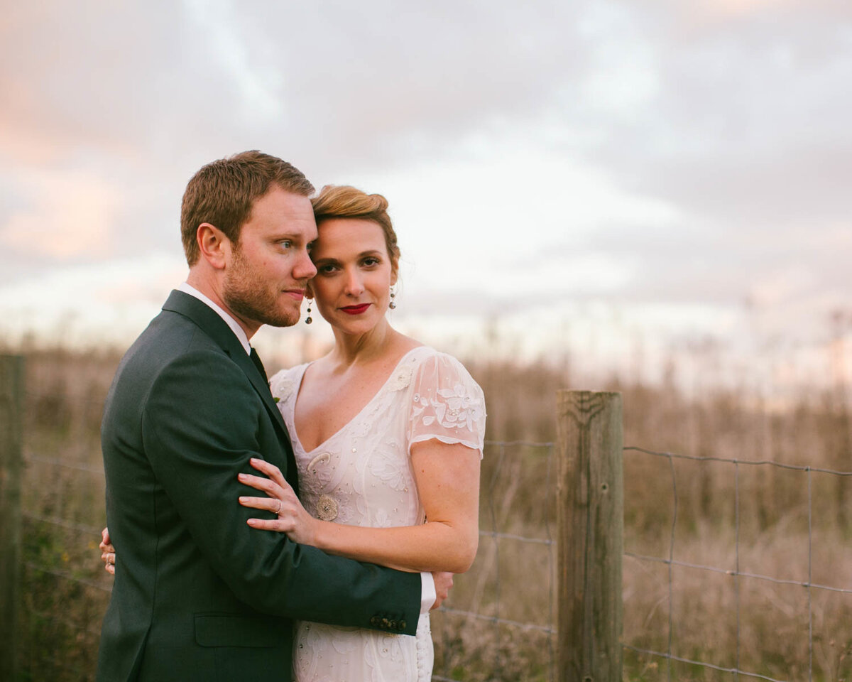 Groom holds Bride looking off as she looks towards the camera