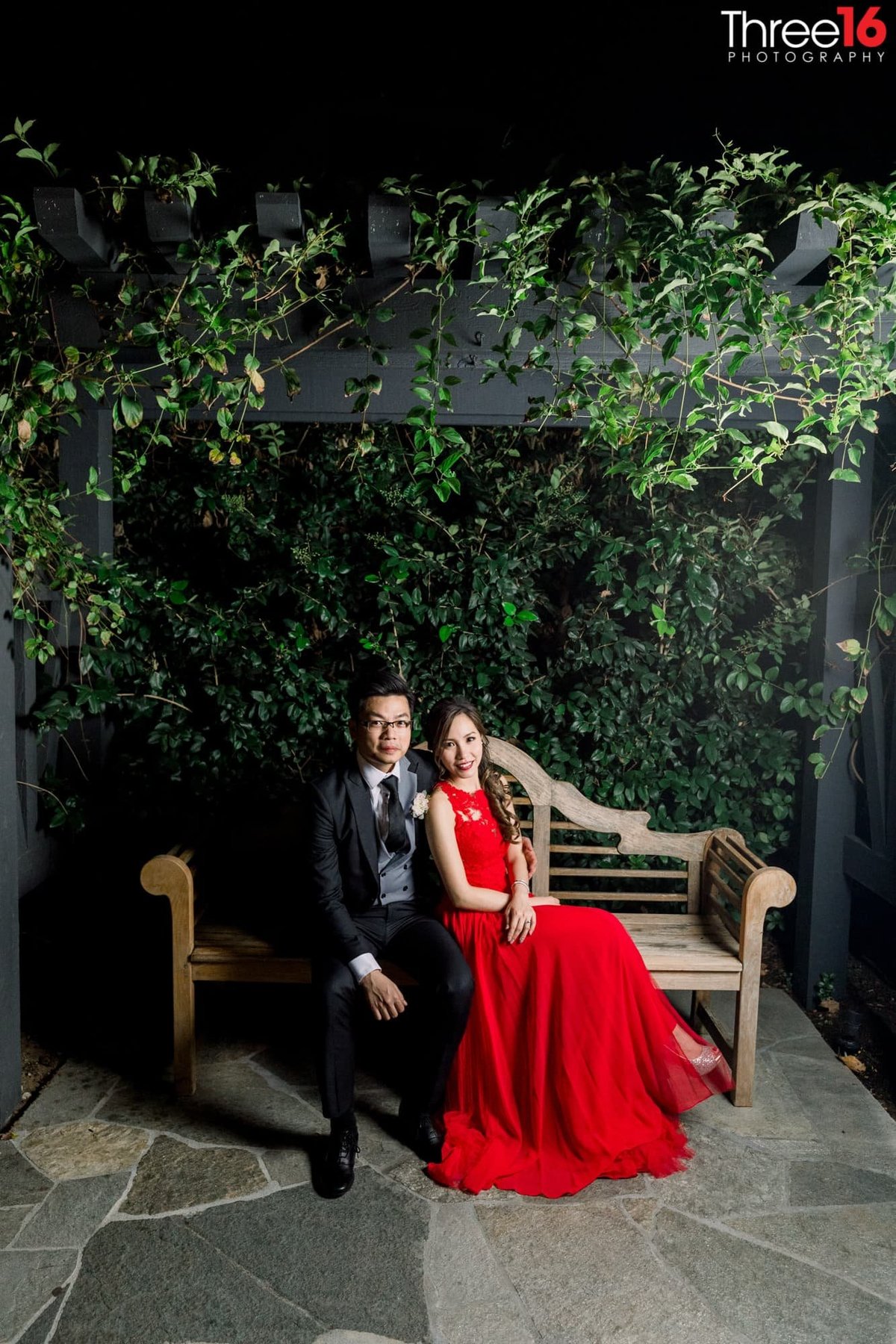 Bride and Groom sit together on a outdoor bench
