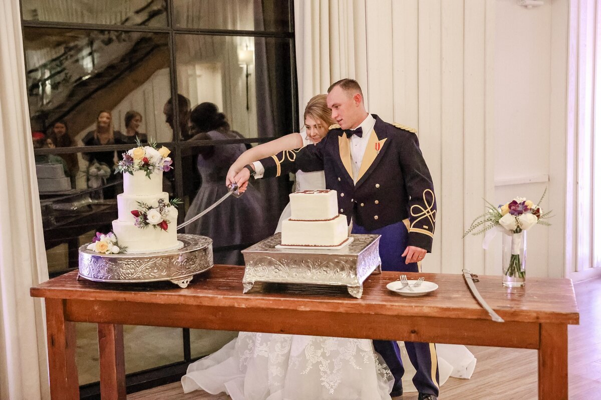 bride and groom cut wedding cake with military saber