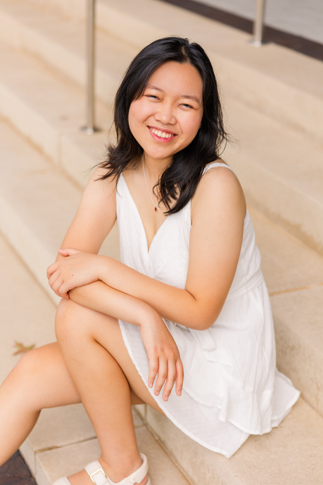 senior girl wearing white dress sitting on steps during photo session with Atlanta photographer Laure Photography
