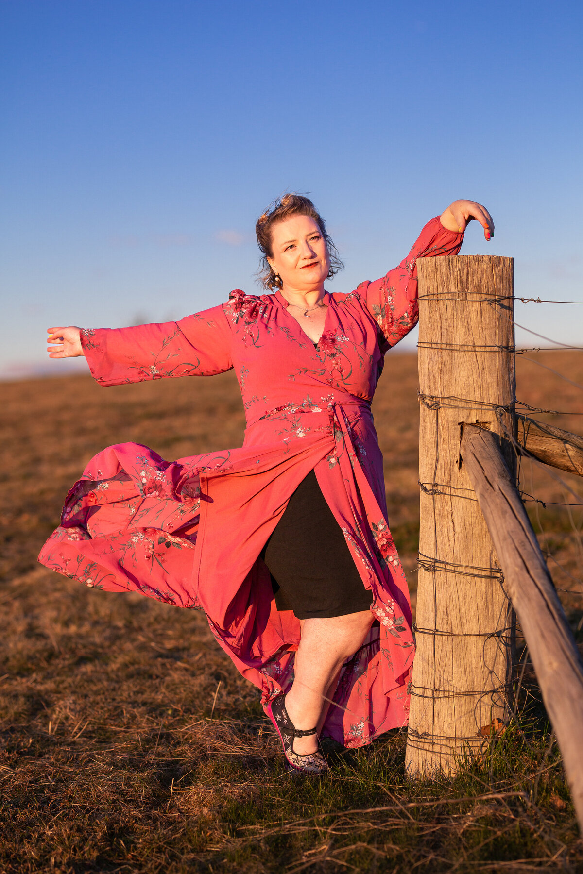 Woman flipping skirt while leaning on fence