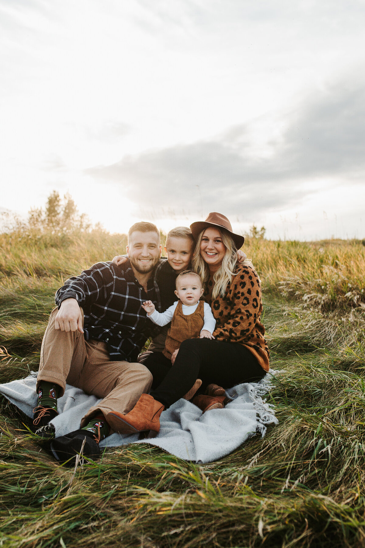 edmonton family posing for fall family photos in a field