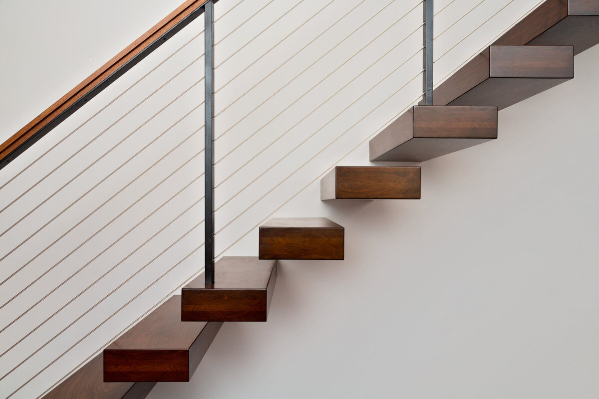 close up of dark wood stairs against white wall