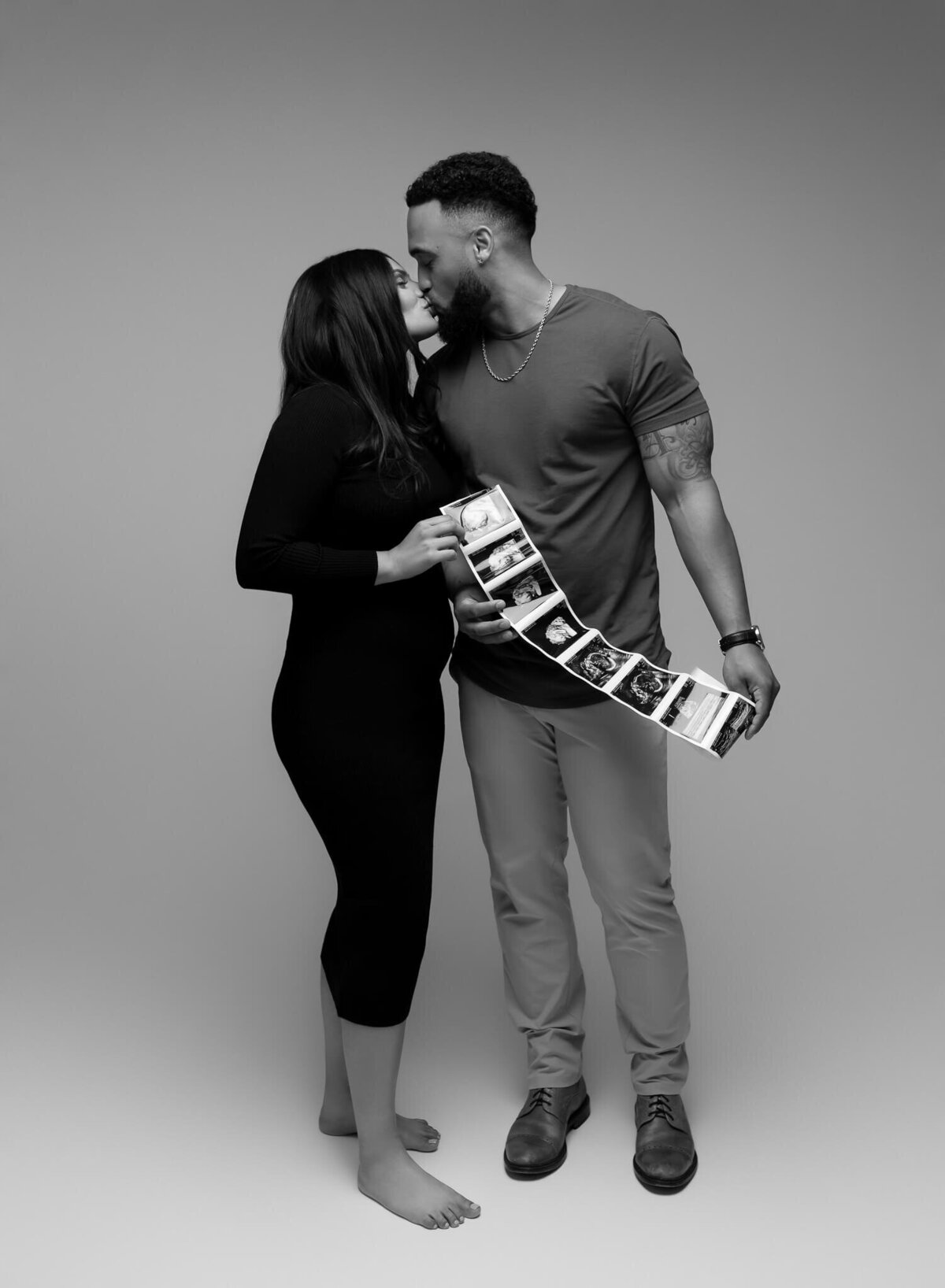 modern black and white pregnancy announcement photo with couple kissing and holding ultrasound