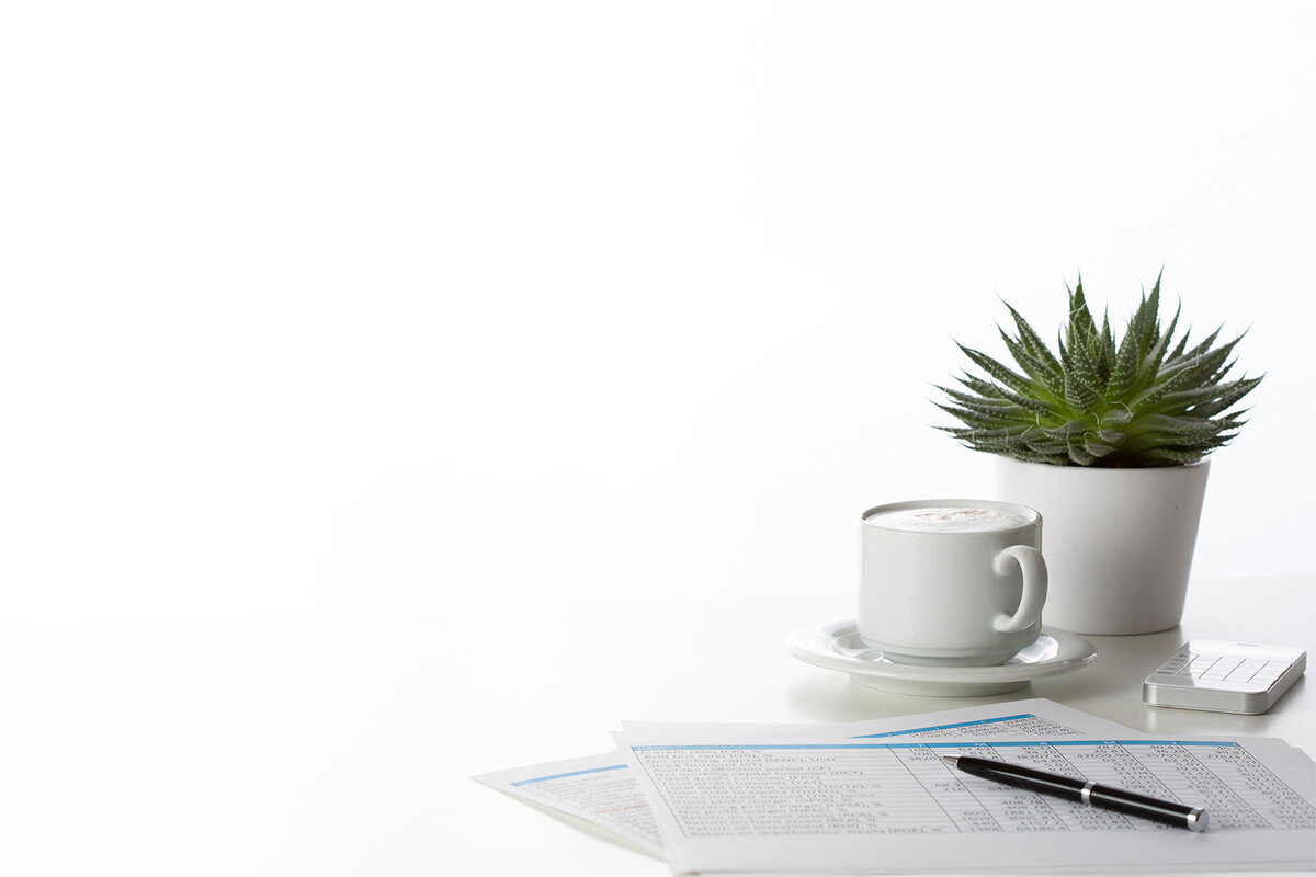 financial sheets with coffee and plant on desk