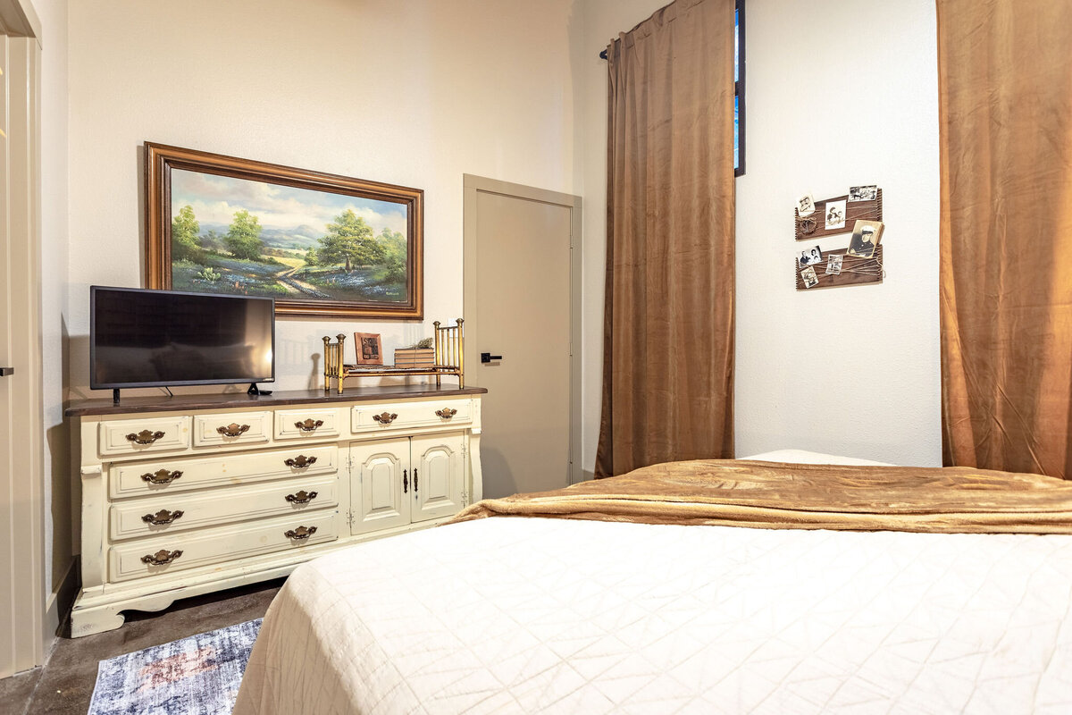 Bedroom with comfortable bedding and smart TV in this 2-bedroom, 2-bathroom vacation rental condo for four guests in the historic Behrens building with free parking, free wifi, vintage decor, and easy access to Baylor University, Magnolia Silos, and Cameron Park Zoo in downtown Waco, TX.