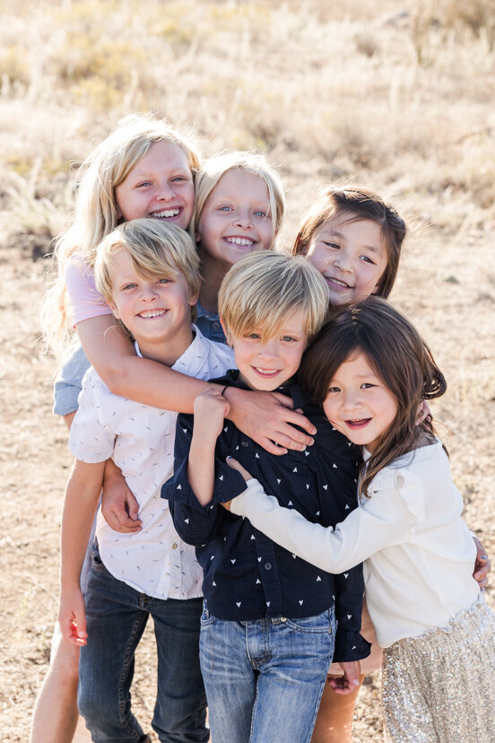 cousins-hugging-family-of-four-sitting-on-rock-wrights-field-san-diego
