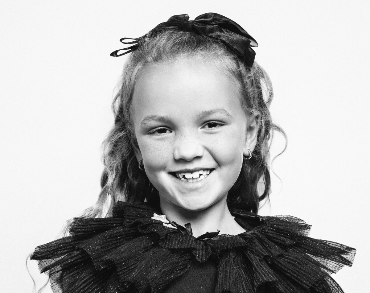 Closeup Black and White Holiday Photo of girl smiling wearing black tulle dress with stars. 