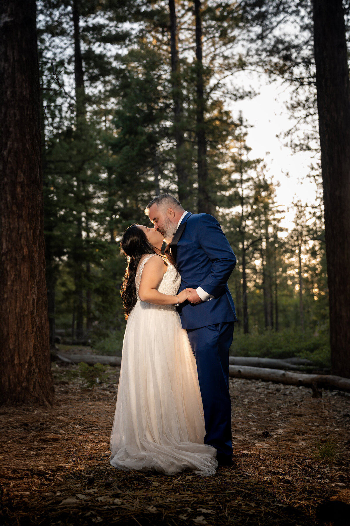 Bride and Groom eloping at Big Bear Buttercup Campground within trees kissing during sunset.