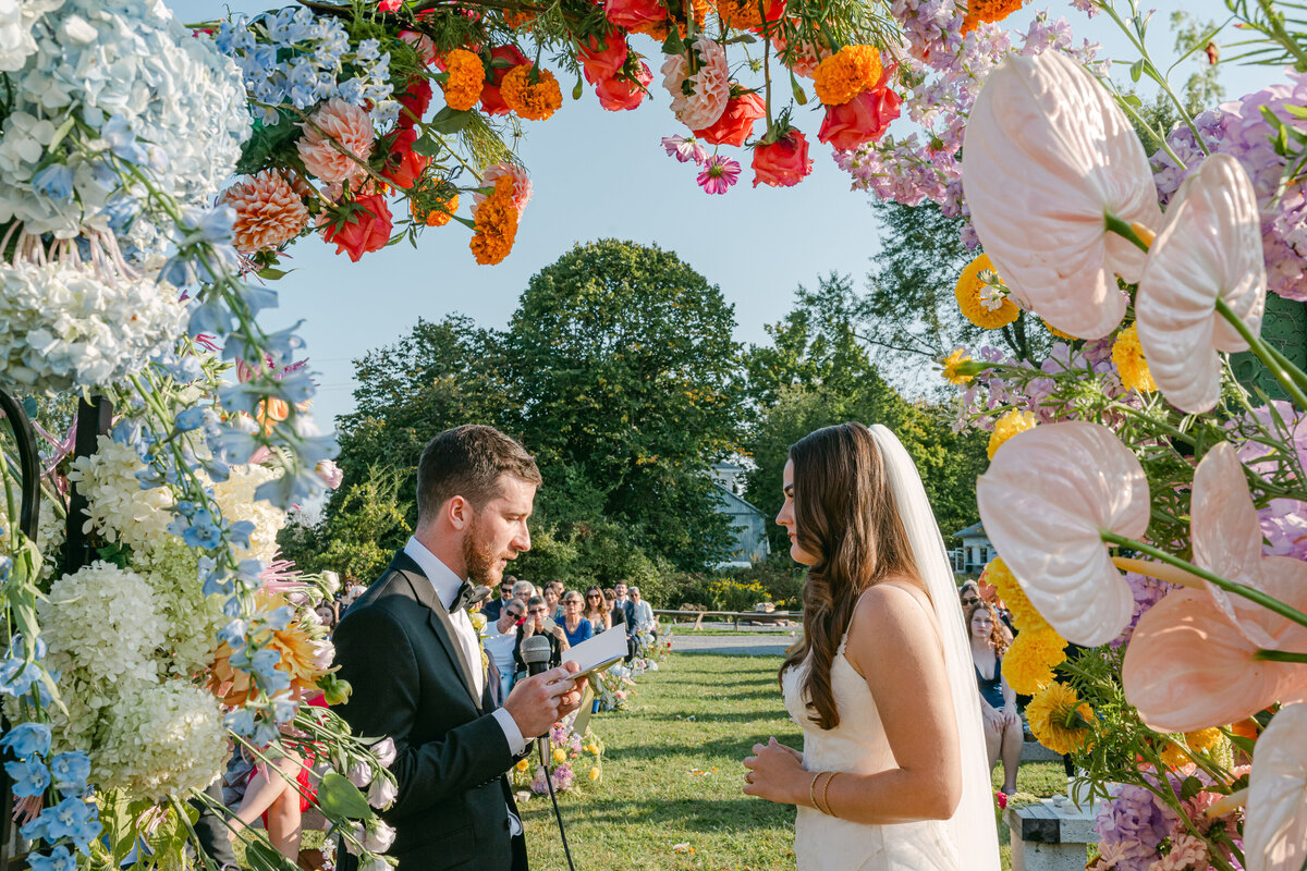 Wedding couple reading their vows under a wild floral arch