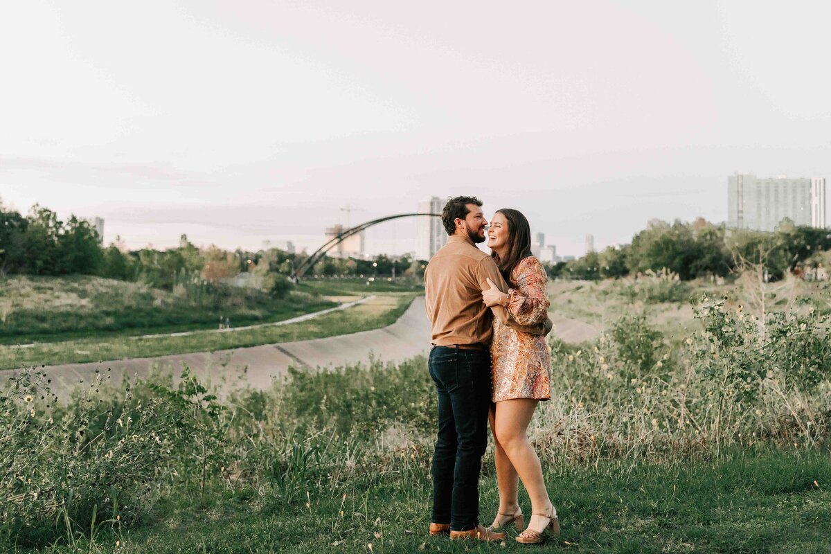 kimberly and garrett hold each other and dance in the grass with the houston skyline behind them.