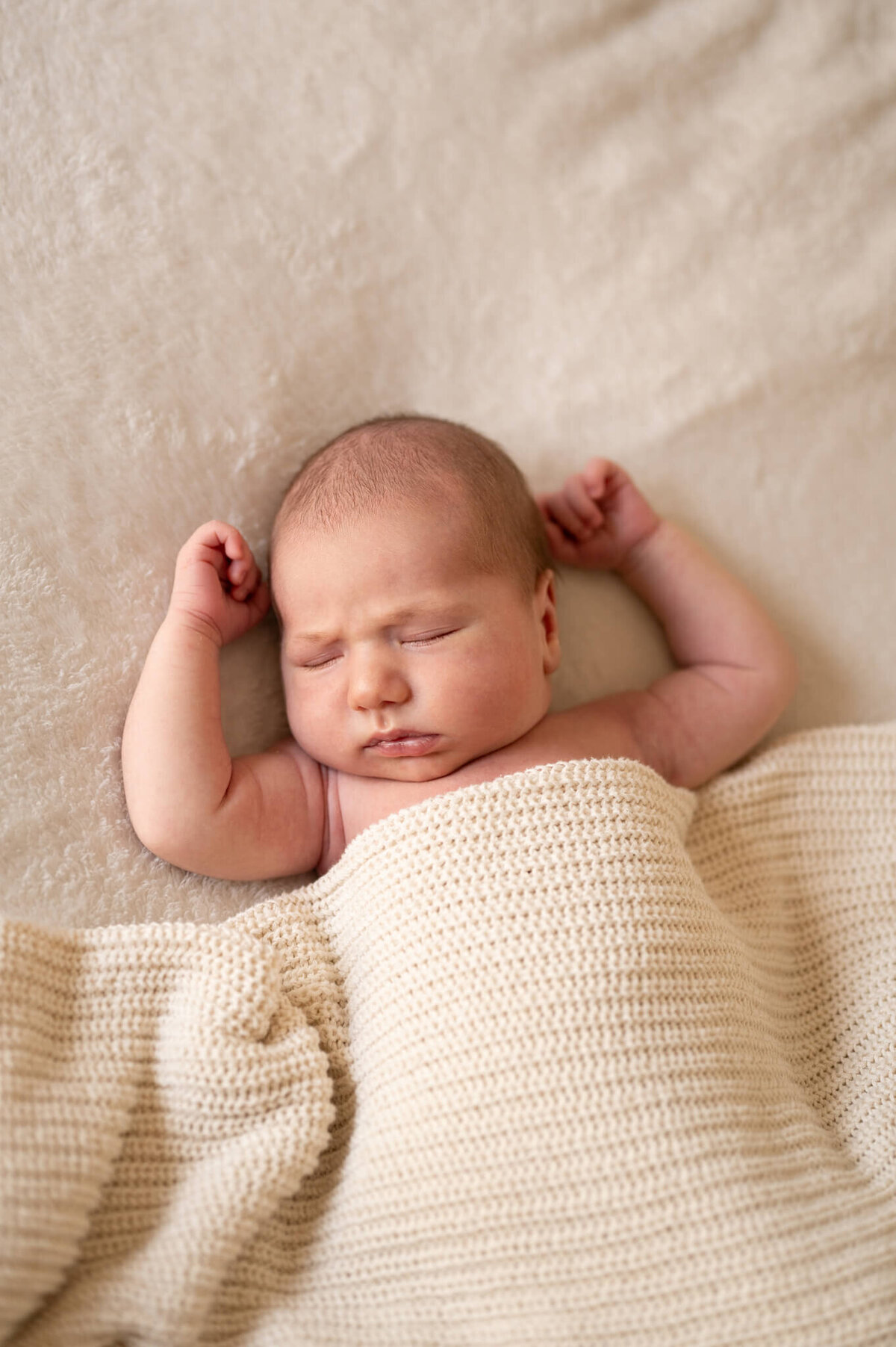 sleeping newborn with grumpy eyebrows on the bed