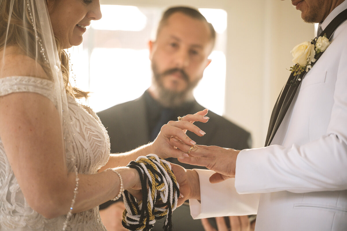 Bride putting ring on groom during wedding ring ceremony.