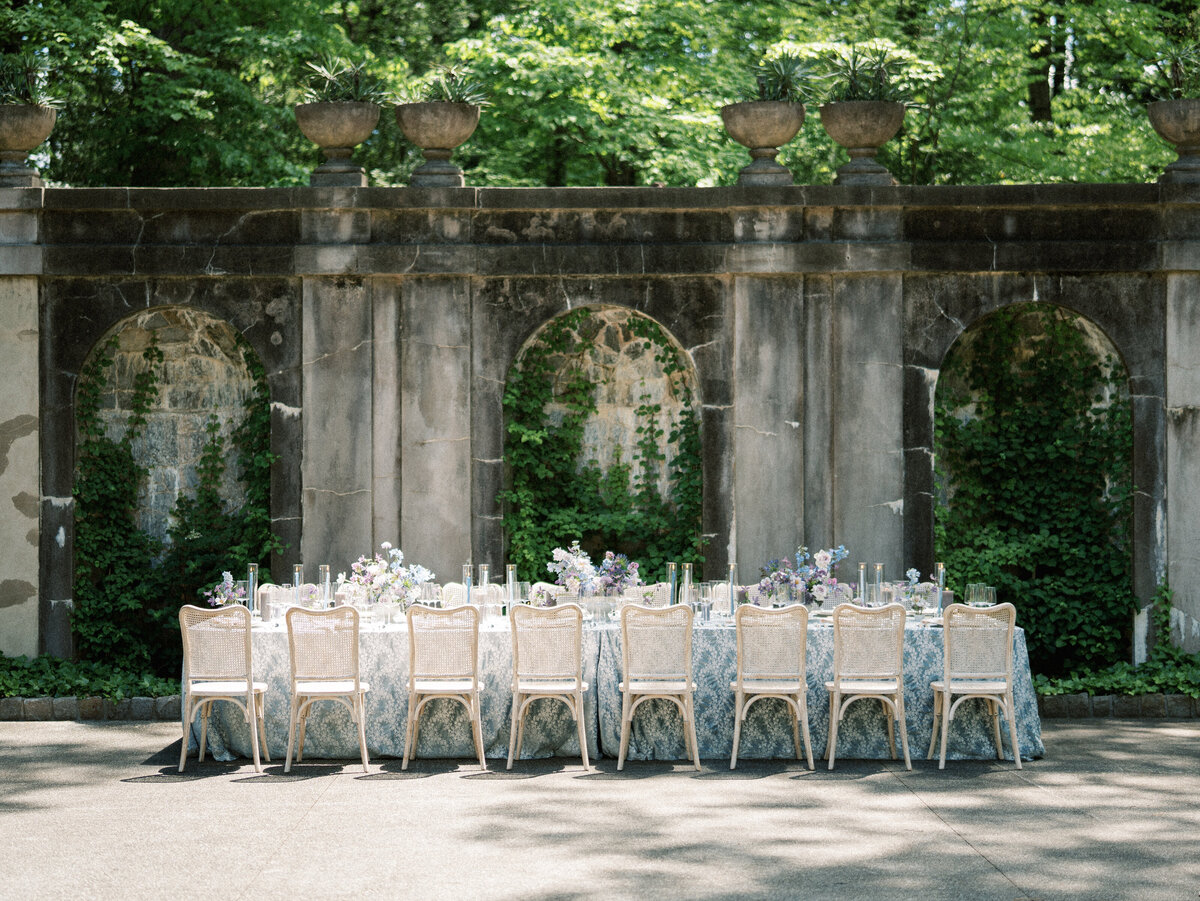Blue and White reception table with light wicker chairs in outdoor garden setting.