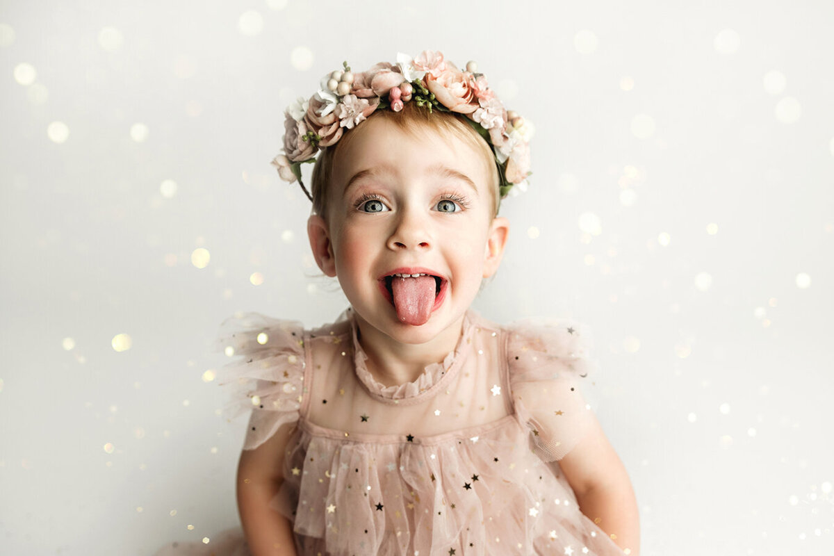 Little girl catching glitter on her tongue in sparkly pink dress