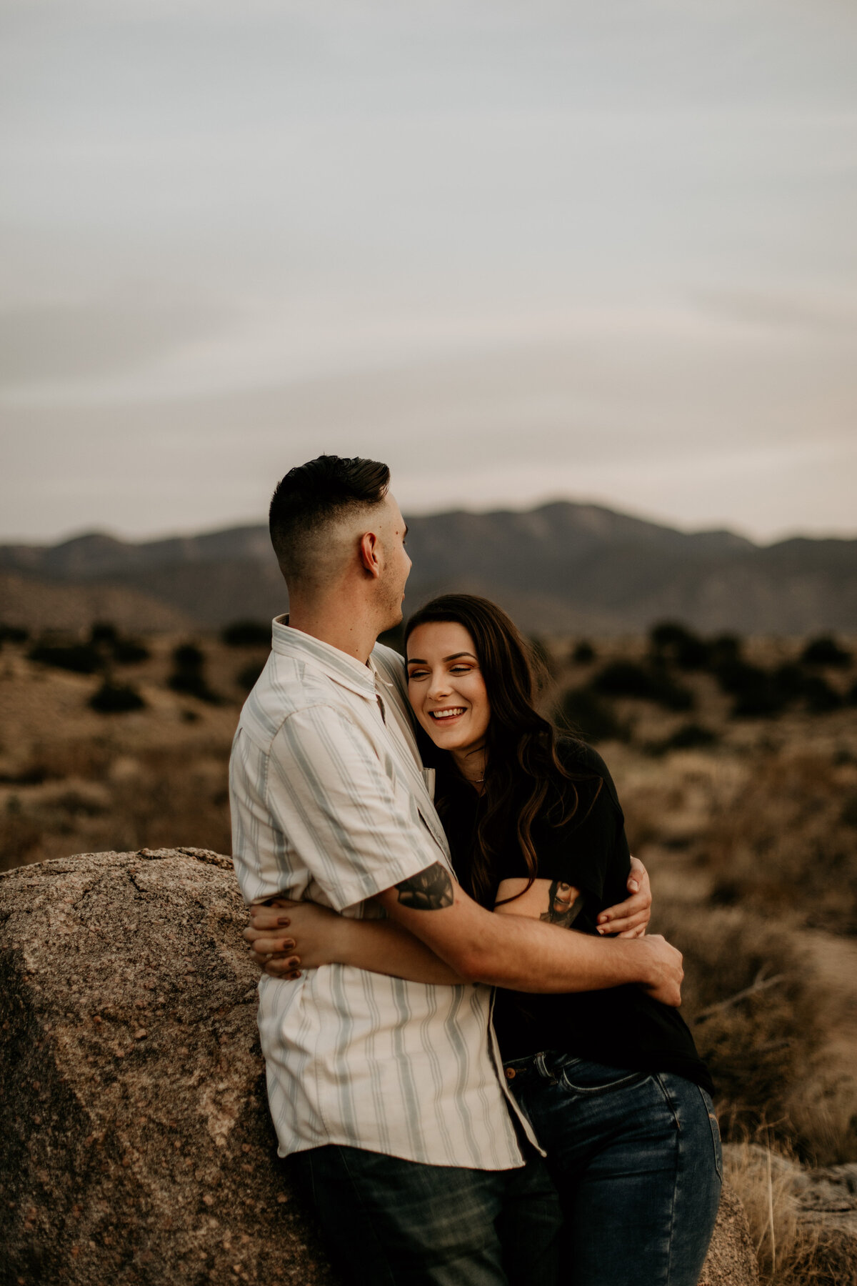 woman hugging and laughing with fiancé in the desert