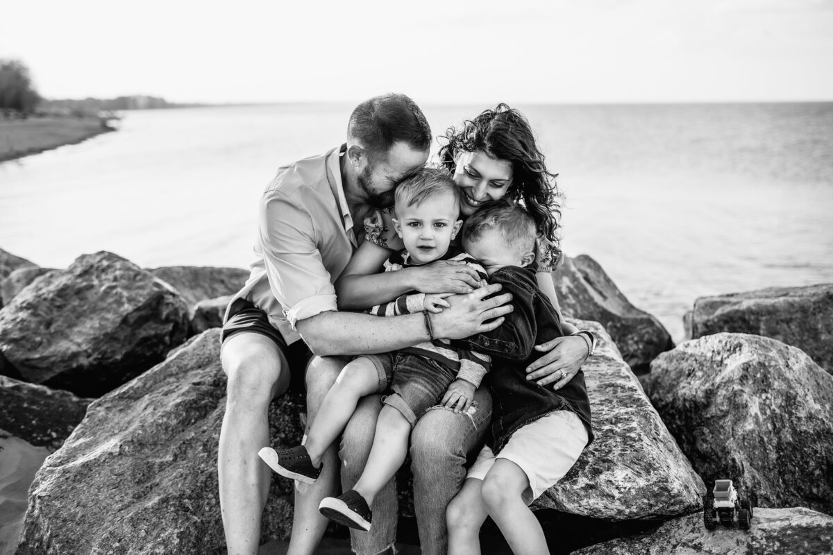 Family hugging at the beach with toddler intensely gazing