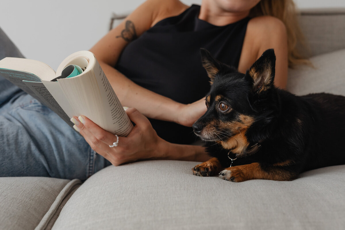 kaboompics_a-woman-reads-a-book-on-the-couch-with-her-dog-28245