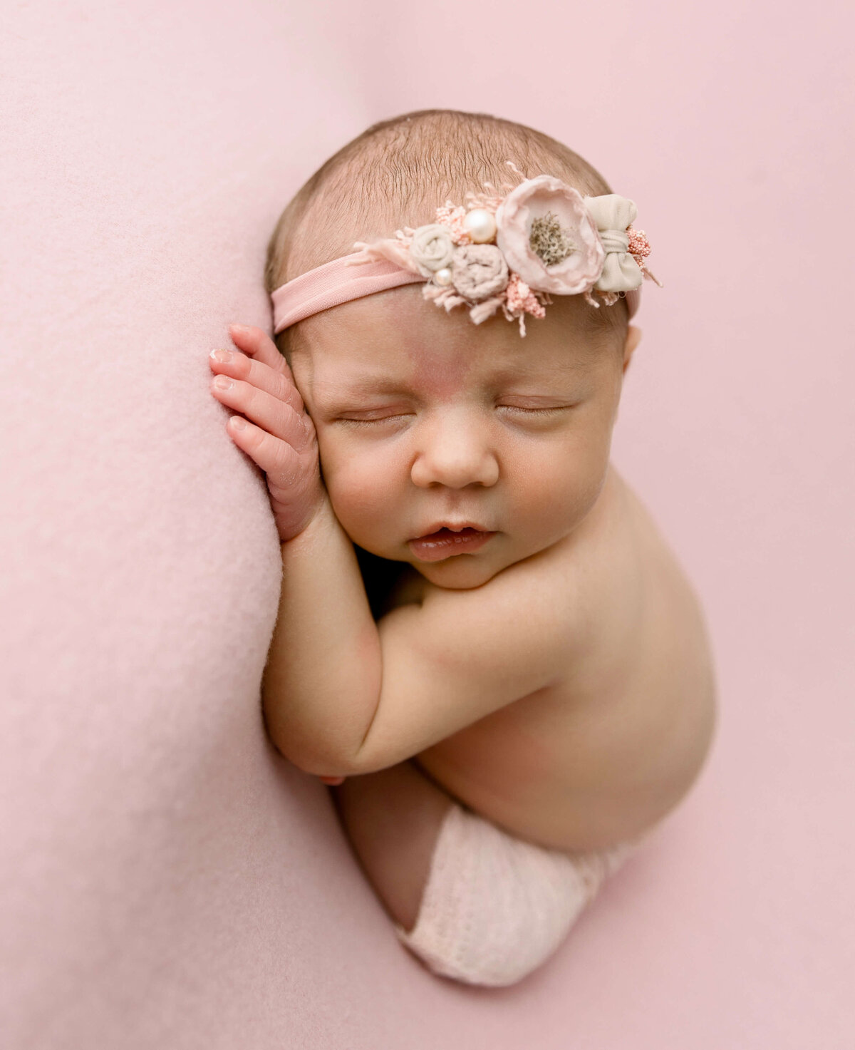 Baby girl in a modified taco pose on a pink backdrop in an Erie Pa photography studio