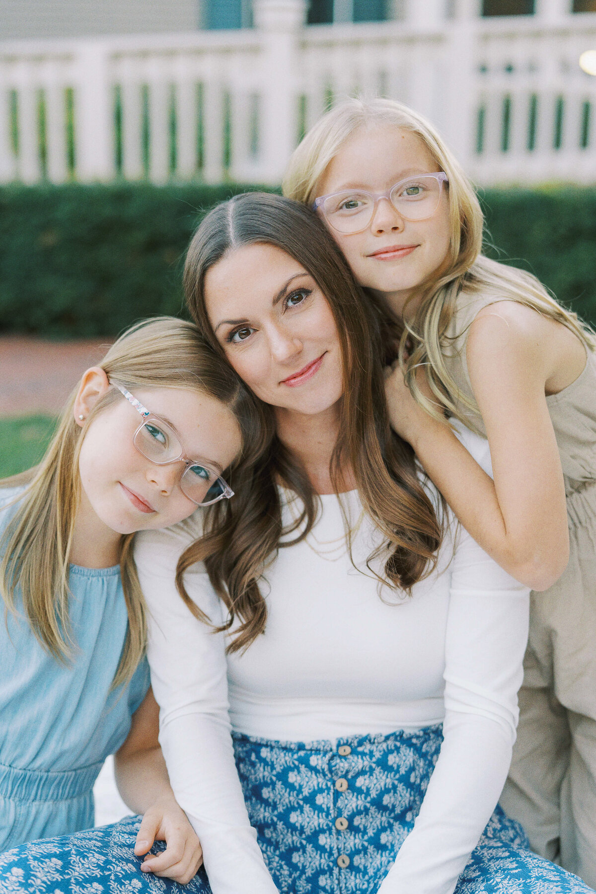 mom and two daughters touching heads together and looking at the camera