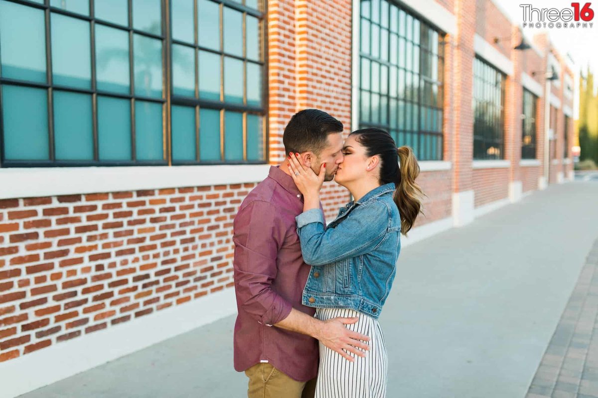 Engaged couple share a romantic kiss outside the Orange Train Station