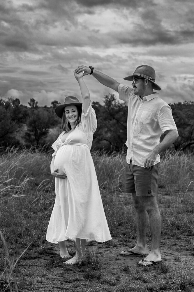 pregnant woman in white maternity gown being twirled by partner - Townsville Maternity Photography by Jamie Simmons