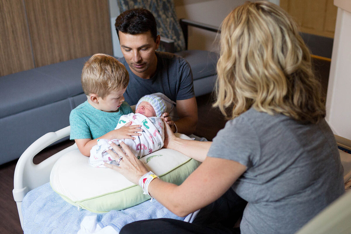 big brother holds baby brother for the first time in mom's hospital room