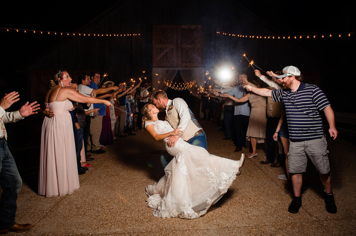 Groom dipping his wife at their sparkler exit outside Drakewood Farm