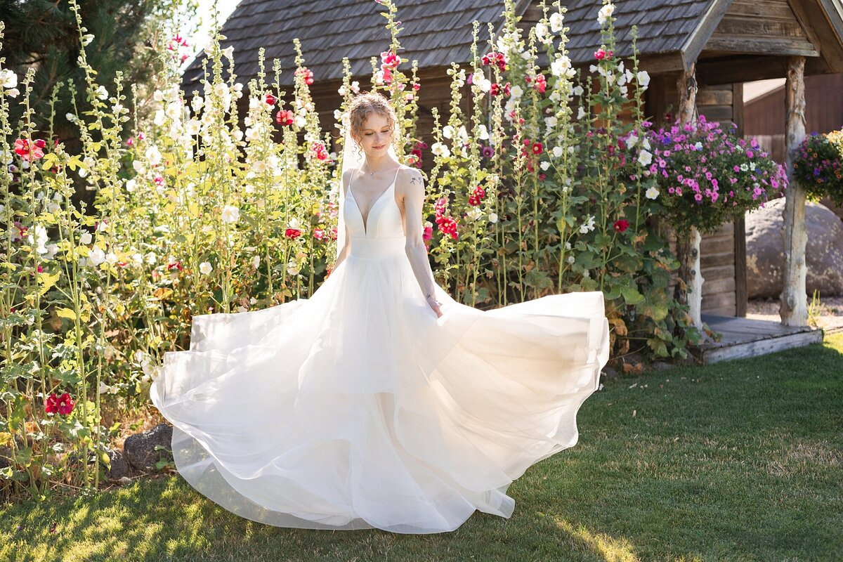 bride twirling in white dress in front of wild flowers