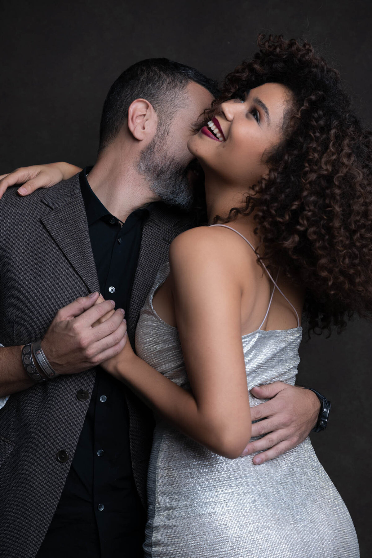 A couple hugging and holding hands smiling and kissing