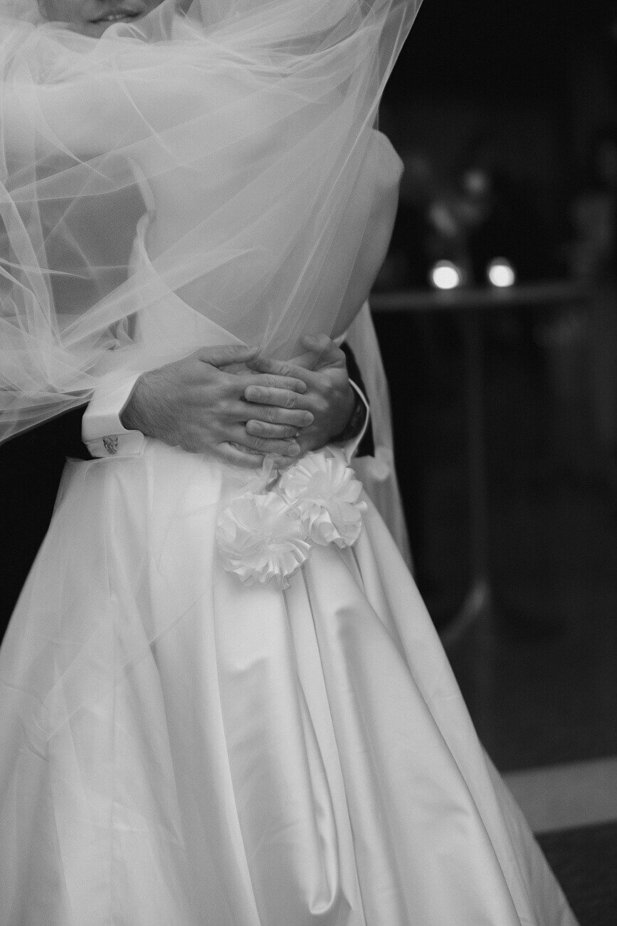 groom's hands wrapped around bride as they share their first dance