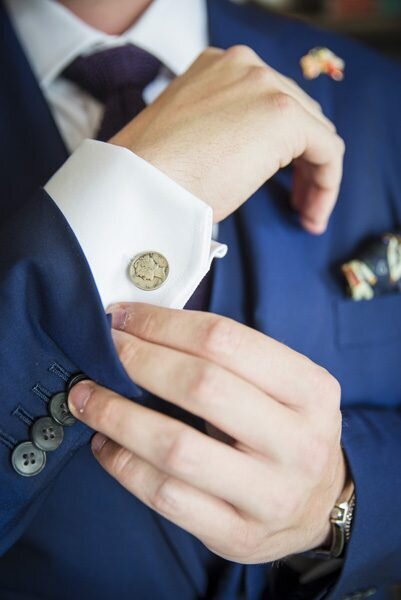 A close up shot of a groom adjusting his sleeve and cufflink.