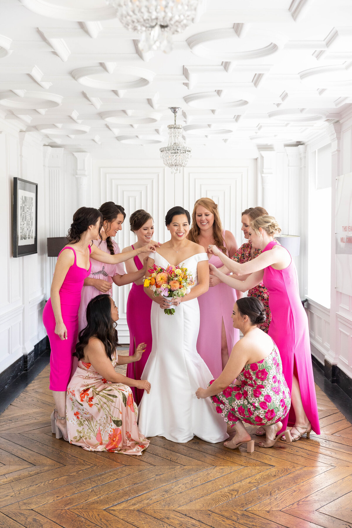 Bridesmaids fixing the bride dress pink, white colors