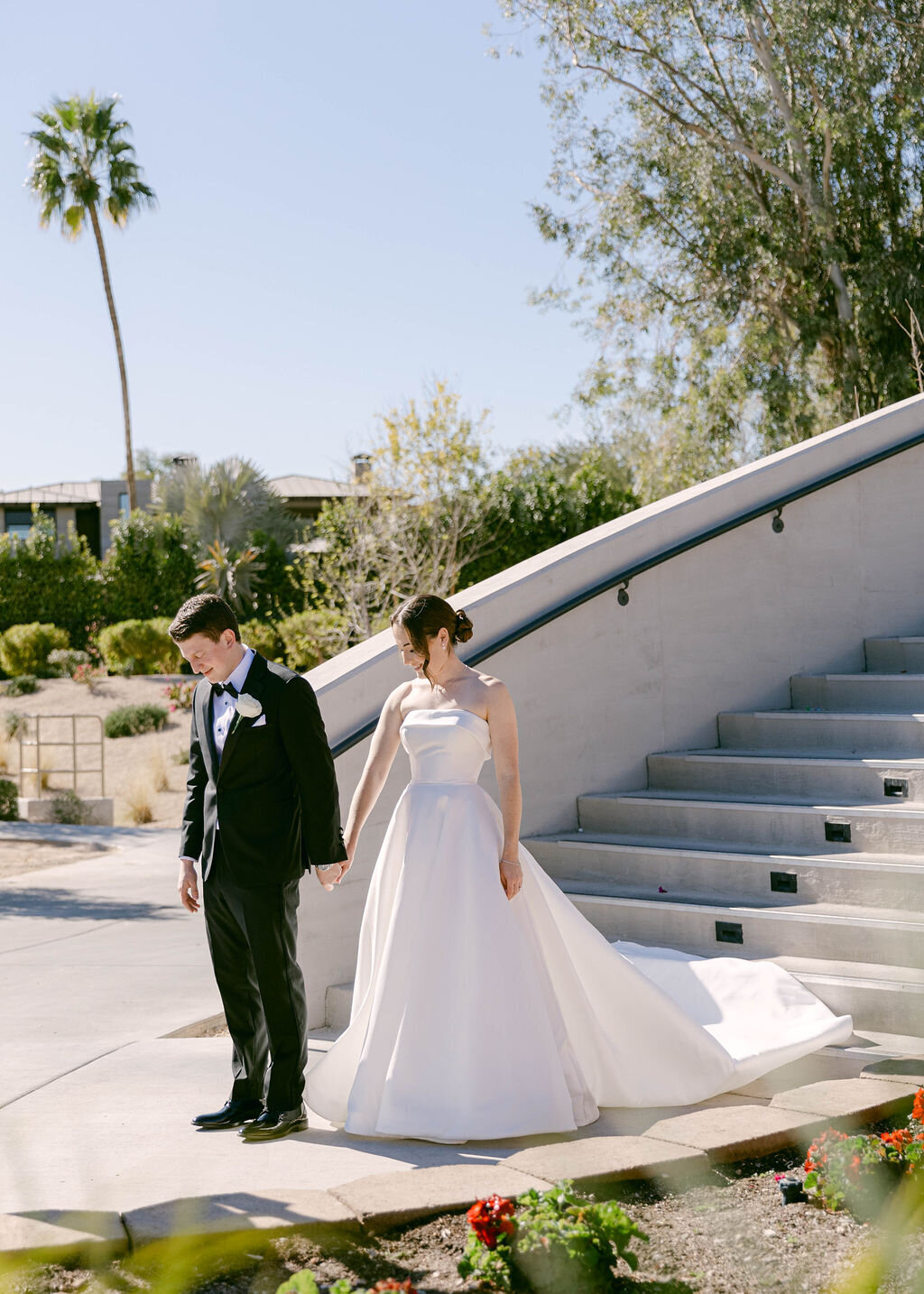 Bride and groom holding hands by modern staircase at Arizona Biltmore Golf Club