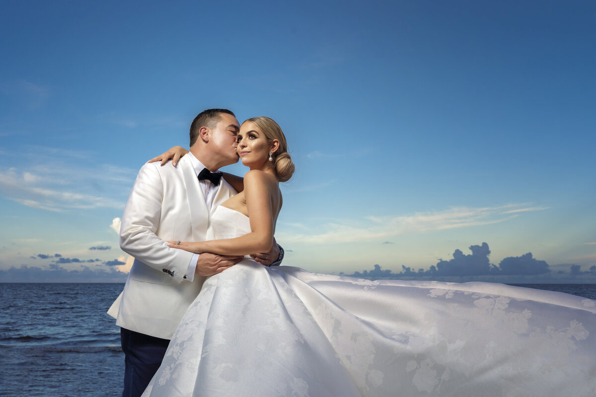 Bride and groom sharing a tender moment by the beach at sunset, captured by Rodrigo Varela Photography.