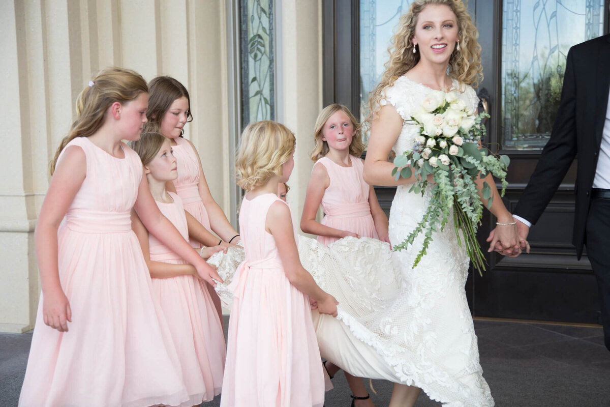 a bride and flower girls holding her train