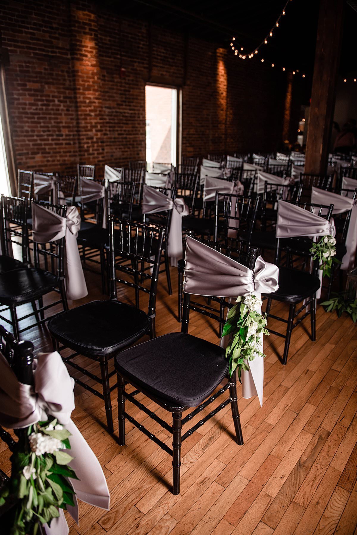 Black chivari chairs with soft blue fabric wraps and Magnolia greenery ties