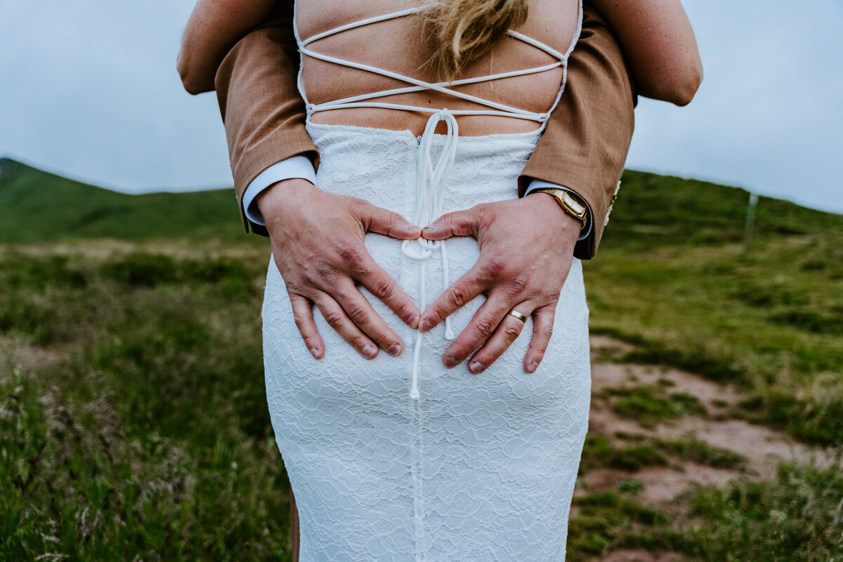 Groom holding bride’s waist on mountain trail