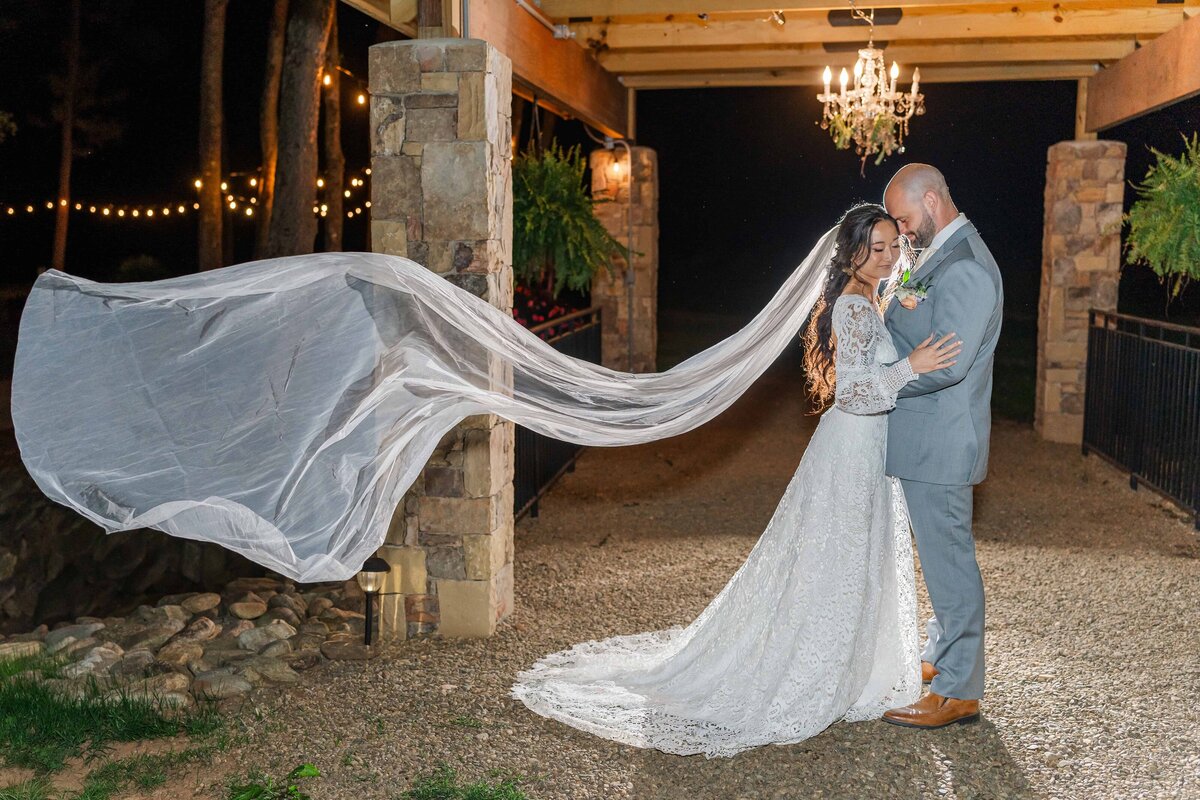 Bride and groom pose under the chandelier at Low Meadows Estate at night