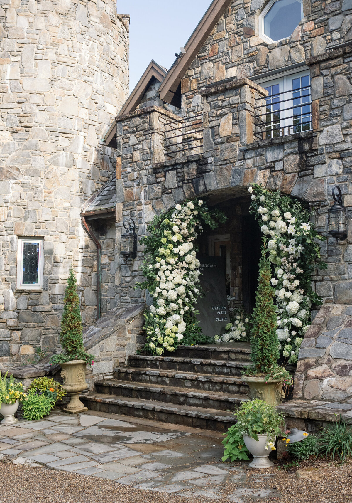 Grand stone castle entrance with an abundant green and white floral arch created for a Highlands wedding ceremony.