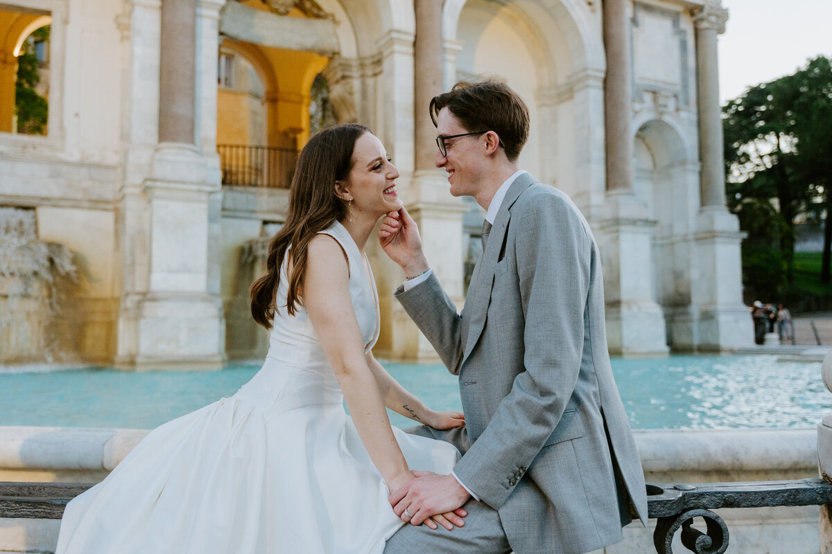 Bride and groom kissing at sunset overlooking Rome.
