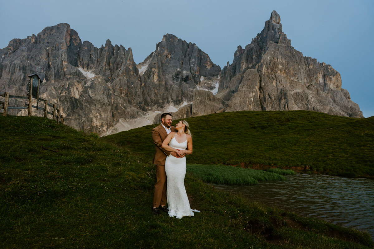 Couple embracing on grassy hill with Dolomites peaks