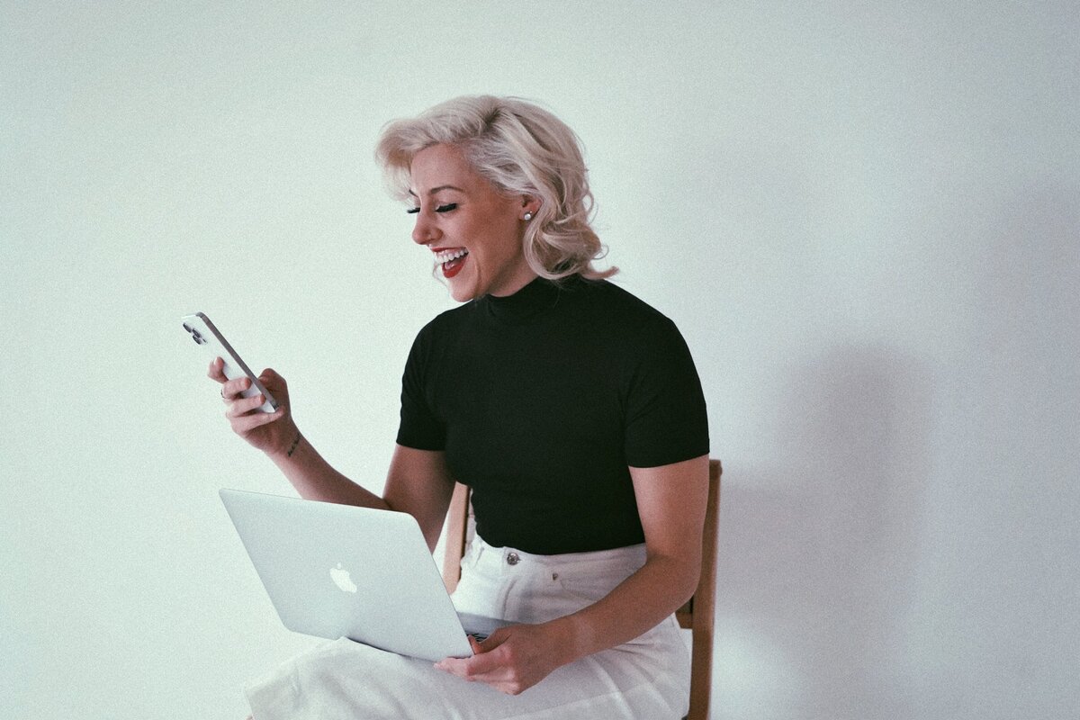 Woman smiling holding laptop and phone