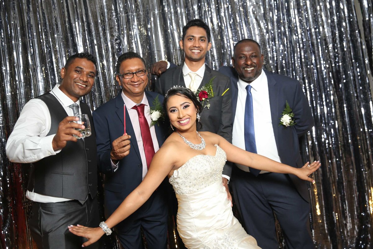 Bride poses with groom and groomsmen. Photobooth by Ross Photography, Trinidad, W.I..