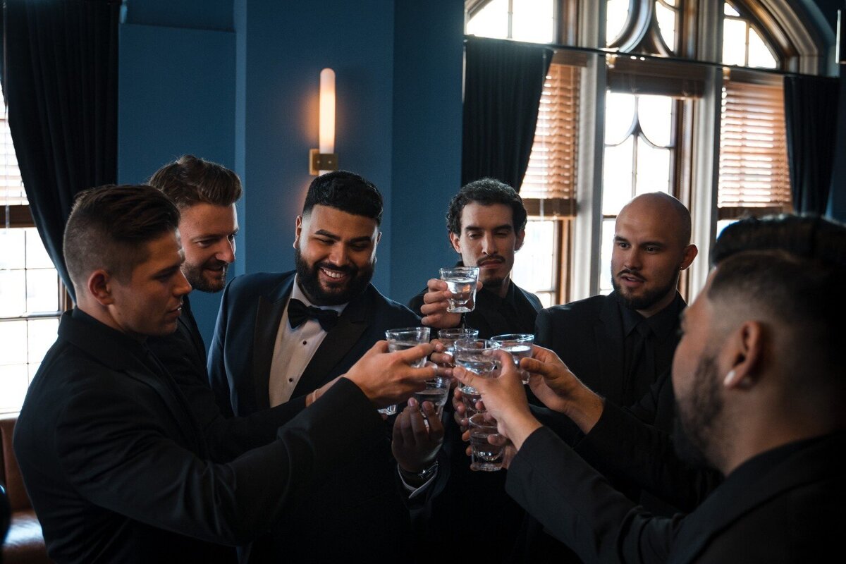 Groomsmen cheering with a toast in the lounge of the Union Club Hotel.
