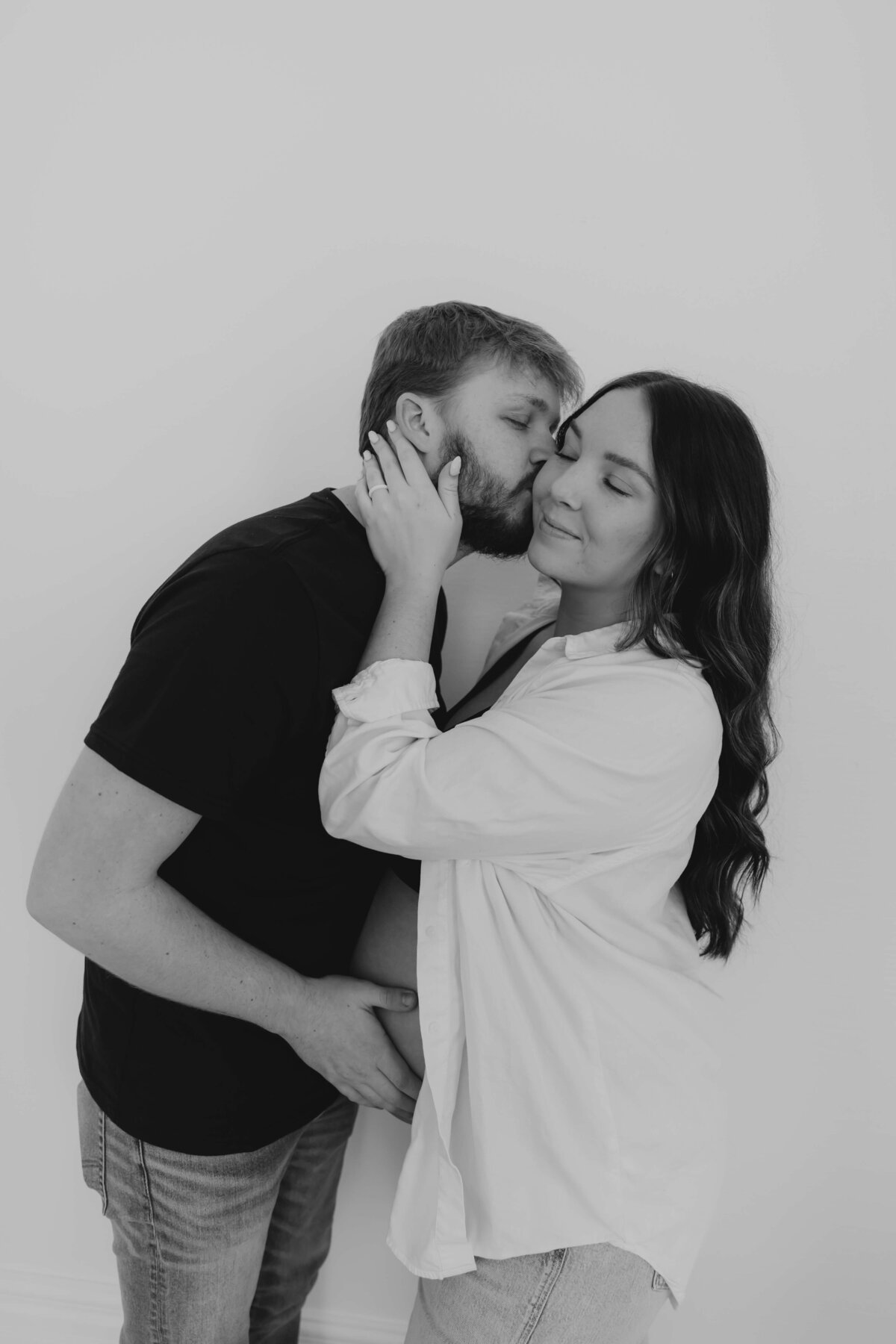 Modern couple embracing during maternity shoot, Ohio studio maternity photography for laid-back parents who want heartfelt, minimalist portraits