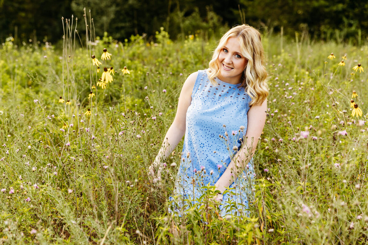 teen girl in a light blue dress sitting in a field of wildflowers