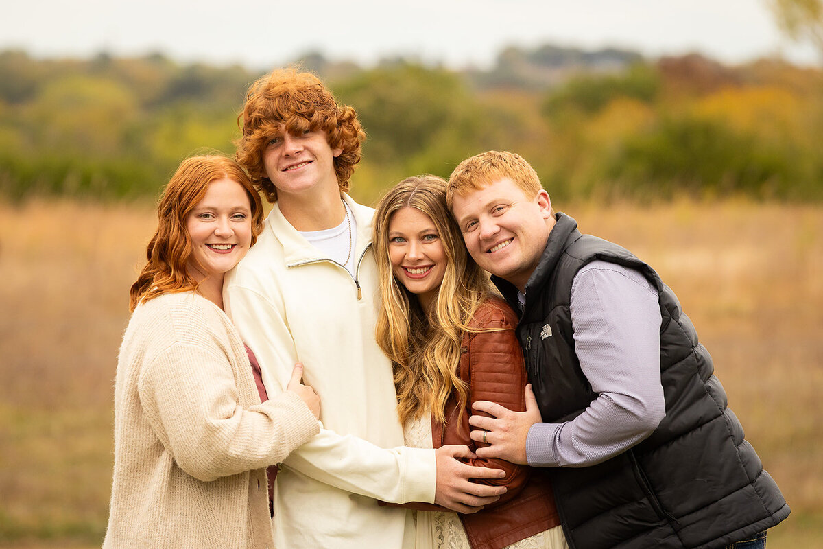 Four red headed siblings laughing and smiling in field
