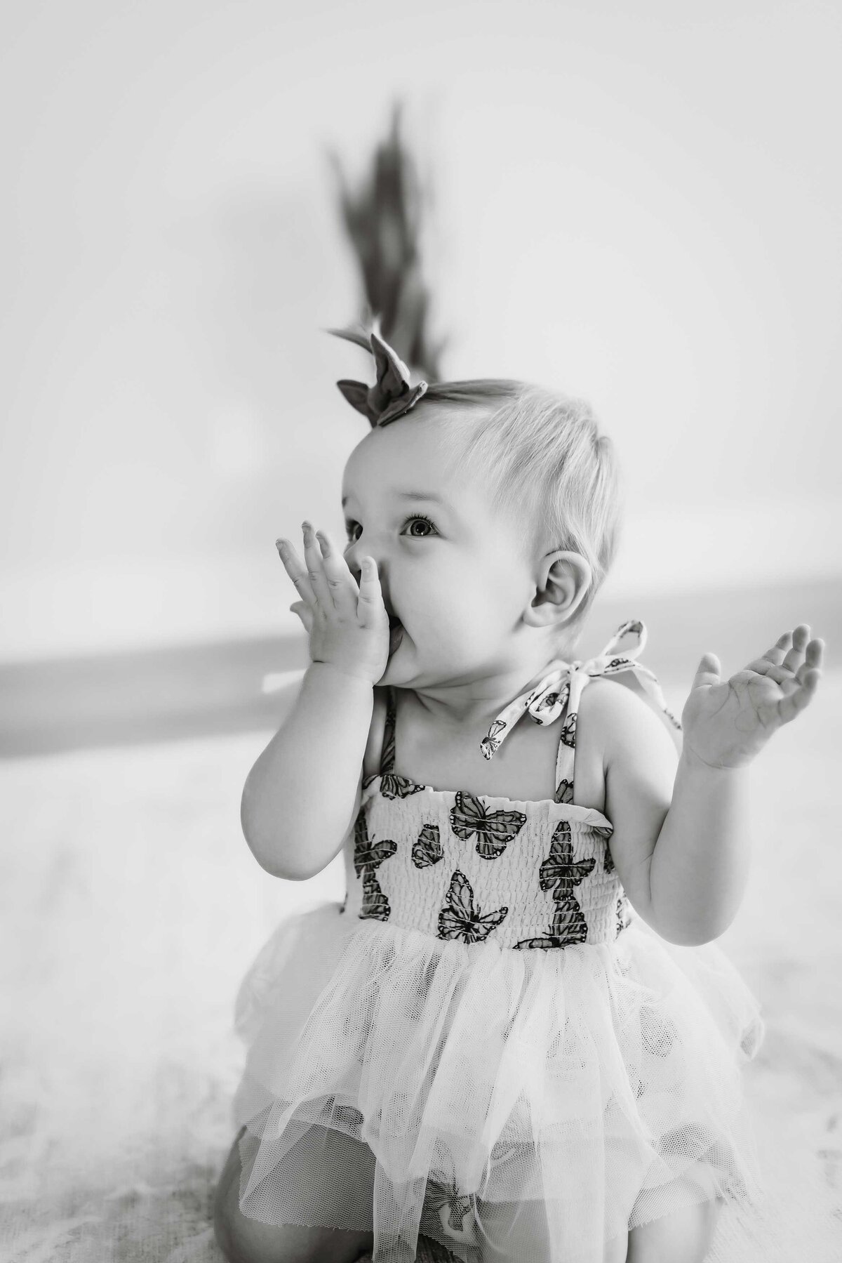 black and white photo of a baby girl blowing a kiss